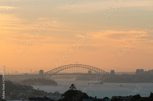 Sydney Harbour Bridge with orange sky at sunset time.