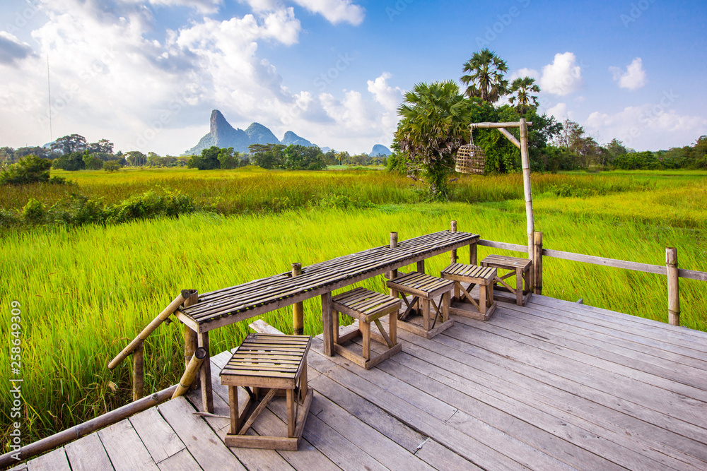 Wooden terrace of coffee shop, cafe, restaurant and tourist in green natural rice field in Thailand. Restaurant Thai country style.