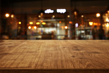Image of wooden table in front of abstract blurred restaurant lights background