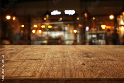 Image of wooden table in front of abstract blurred restaurant lights background © tomertu
