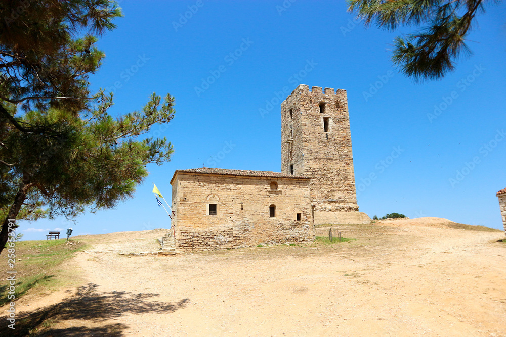 view of ancient church and ancient byzantine tower in Nea Fokea, Greece surrounded by pines