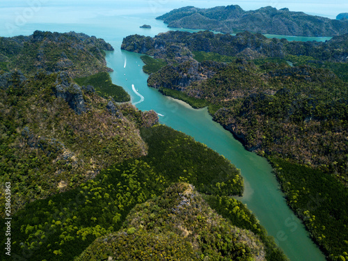 Aerial view of bay and river in Park Kilim Geoforest, Langkawi, Malaysia. Beautiful mountains, sea and trees around the river. Boat sailing on the river © dimabucci