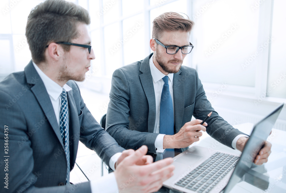 close up.business colleagues discuss something sitting at the Desk.