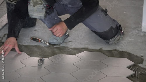 Professional worker laying hexagon stone mass tiles on floor
