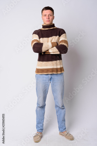 Full body shot of young man wearing turtleneck sweater with arms crossed