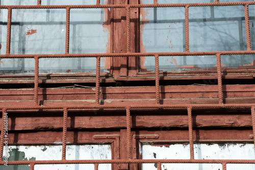 Old painted window behind rusty grate close up