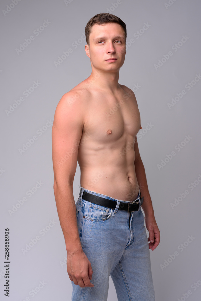 Portrait of young muscular shirtless man thinking and looking at distance
