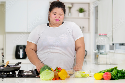 Overweight woman preparing meal in the kitchen