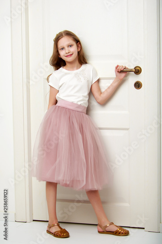 A little girl is standing by the door.