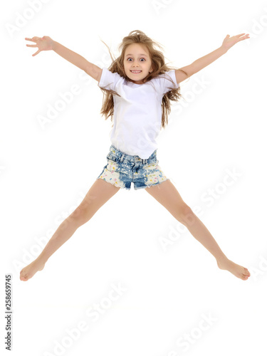 A little girl in a pure white t-shirt is jumping. The concept of