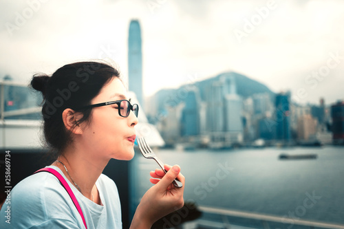 Asian woman eating cake on Victoria harbour Hong Kong