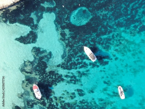 Vistas aereas de una cala de Mallorca sobre unas aguas color turquesa con unos barcos anclados 