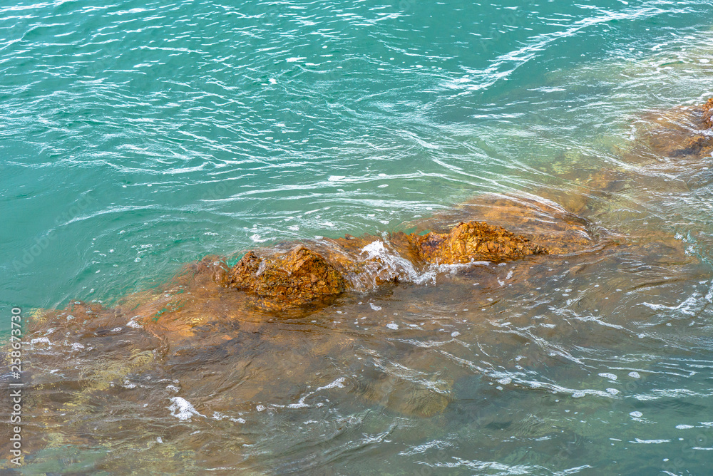 Obraz premium Sea waves breaking on a rocks. Deep blue sea waves hit cliff, hit rocks cliff. Mighty sea waves breaking on a cliff, splashing over rocks. Strong ocean waves hitting rocks.