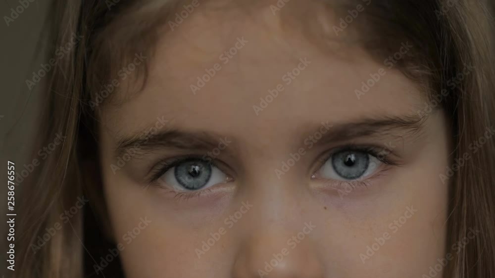 Portrait little young girl with blue eyes looking at camera. Young serious child looking at camera. Closeup. Indoors. Sad little kid girl portrait looking. Portrait little young girl with blue eyes looking at camera. Young serious child looking at camera. Closeup. Indoors. Sad little kid girl portrait looking.