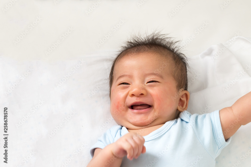 Happy little Asian baby smiling while lying on white bed Happy little Asian baby smiling while lying on white bed