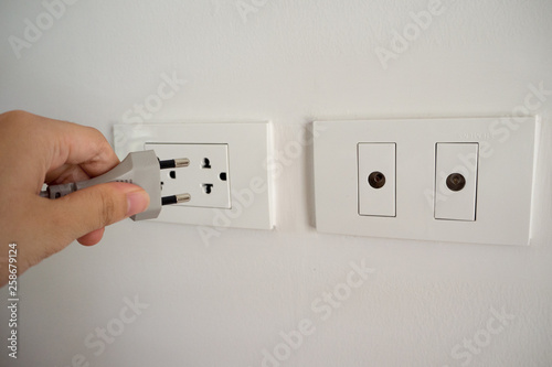 Hand putting plug in electronic power socket