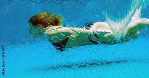 Woman underwater in a glass swimming pool