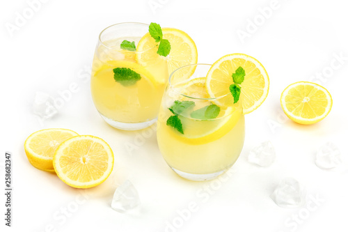 A photo of homemade lemonade in glasses, with fresh lemons, mint, and ice cubes, on a white background with a place for text
