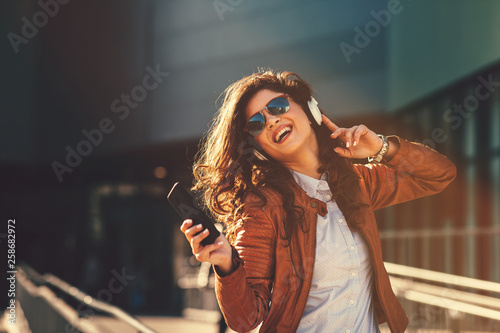 Young modern woman enjoys music on the street via headphones