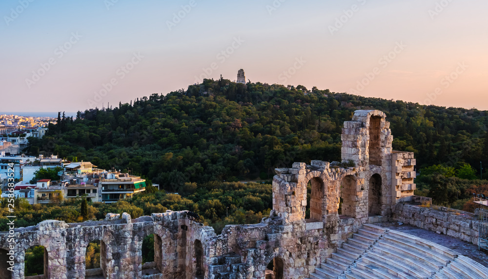 View of Odeon of Herodes Atticus theater on Acropolis hill, Athens, Greece, overlooking the city and hill of Muses or Philpppapou at sunset