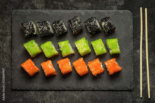 Top view set of assorted japanese sushi food on a black stone plate and sushi sticks. Rolls with tuna, salmon, shrimp, crab and avocado. Sushi menu. photo