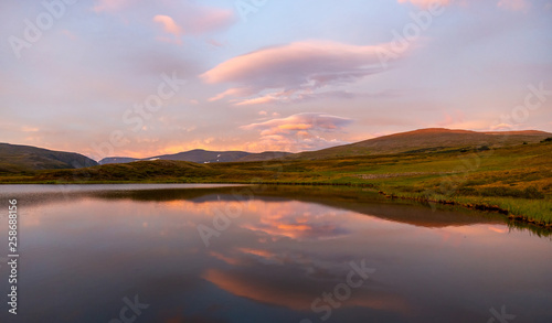 Summer landscape in the tundra with a lake in the mountains in sunrise