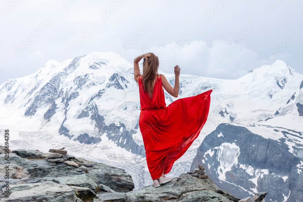woman in long red dress on background of glacier - obrazy, fototapety, plakaty 