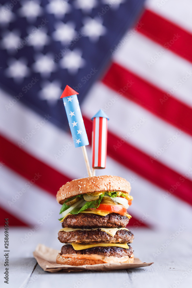 a big burger with three juicy beef patties bonded with American flag firework skewers. burgar
