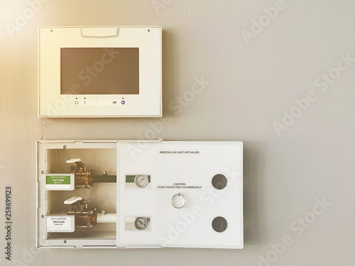 Medical oxygen air and vacuum electronic control panel with valves and gauges in service box installed on white wall in emergency zone at hospital.