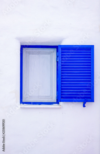 White and blue windows on a wall with shutters