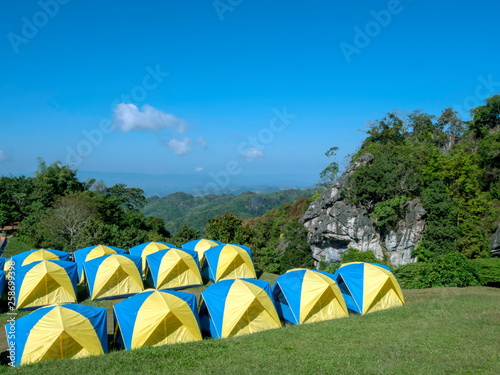 A colorful group of tents camping set up on the hill with a blue sky background