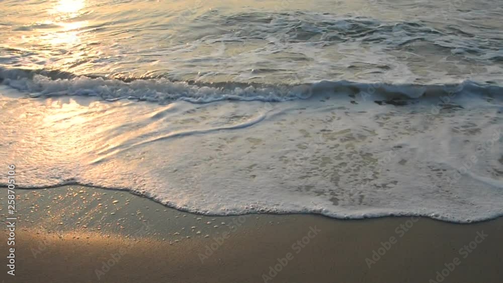 Calm waves splashing onto a tropical white beach at sunset in Thailand. Calm waves splashing onto a tropical white beach at sunset in Thailand.