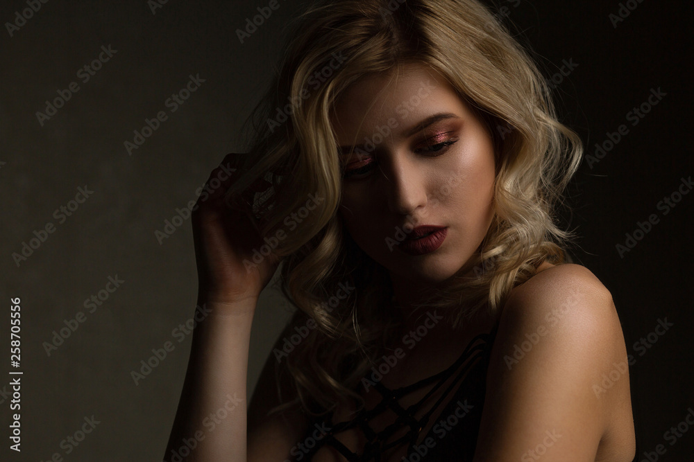 Sensual blonde model with perfect makeup and naked shoulders posing with contrast light. Empty space Sensual blonde model with perfect makeup and naked shoulders posing with contrast light. Empty space