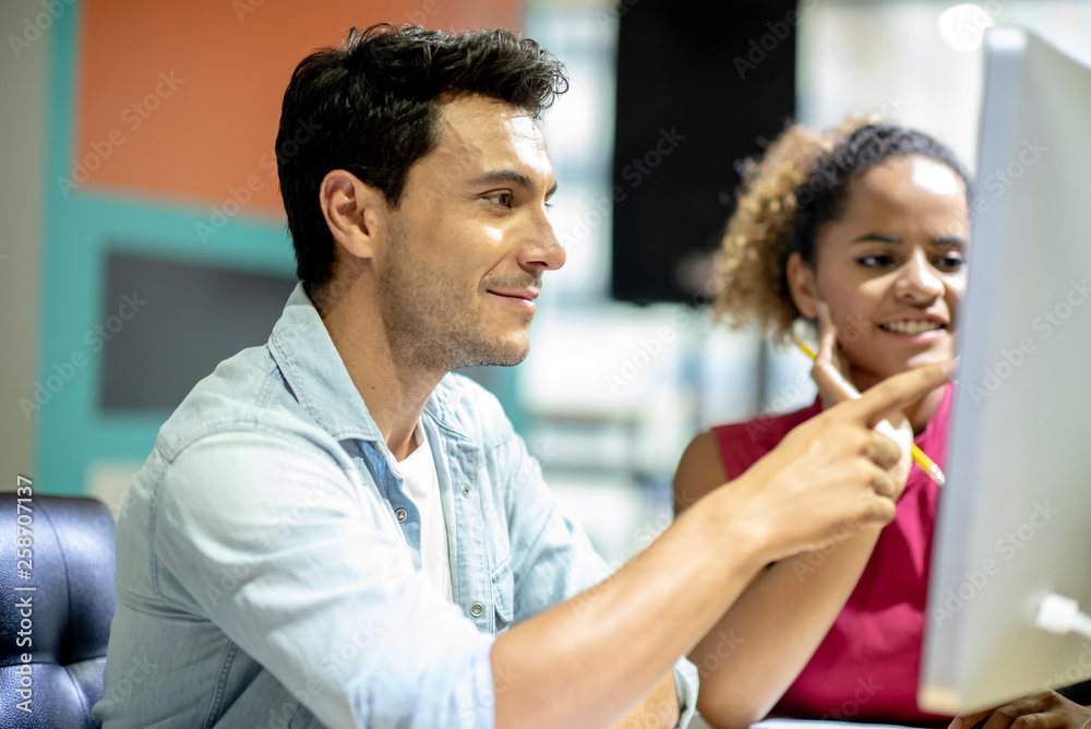 Two young colleagues in smart casual wear discussing something while spending time in the office,African girls learn to work from handsome man by computer Two young colleagues in smart casual wear discussing something while spending time in the office,African girls learn to work from handsome man by computer