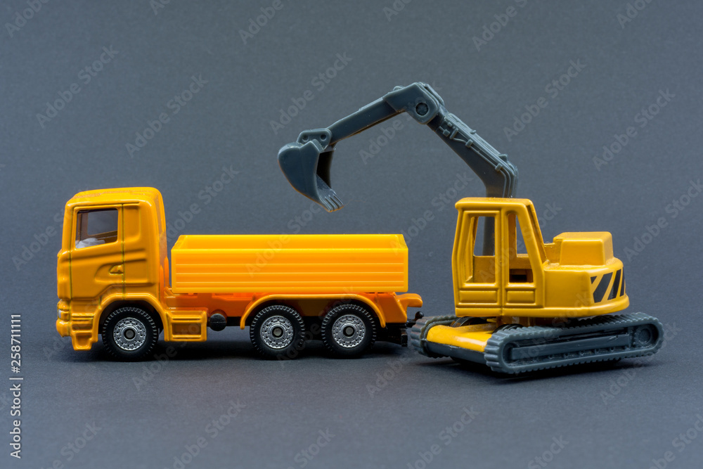 Diorama road construction with yellow construction machinery models. Construction concept. Children's toys of construction machinery. Toy truck and excavator on gray background. Construction concept.
