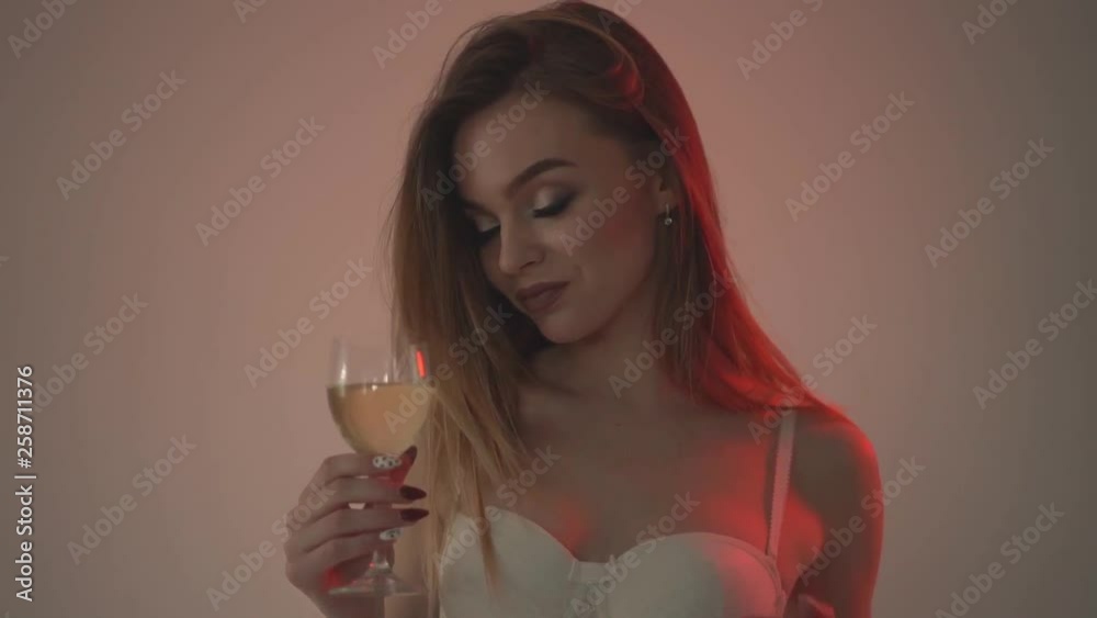 The girl drinks white wine, close-up and red backlight. . Slow motion 60fps