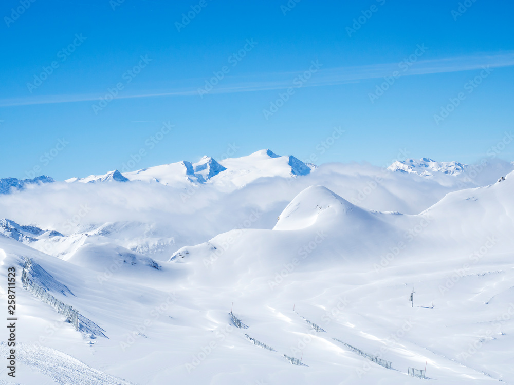 Winter landscape with snow covered slopes and blue sky, view from the top of Kitzsteinhorn mountain on . Kaprun ski resort, National Park Hohe Tauern, Austrian Alps, Europe.