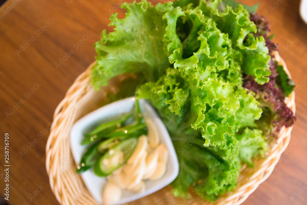 Fresh lettuce, garlic and chili slice on basket at korean barbeque restaurant Fresh lettuce, garlic and chili slice on basket at korean barbeque restaurant