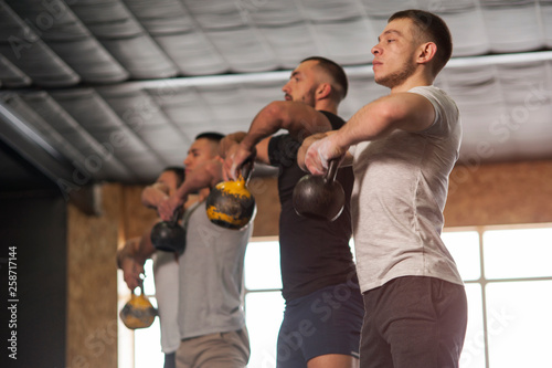 Group of Fit and Focused Men Training With Kettlebells