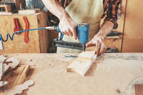 Tablou canvas Carpenter using nail gun to crown wooden boards in workshop