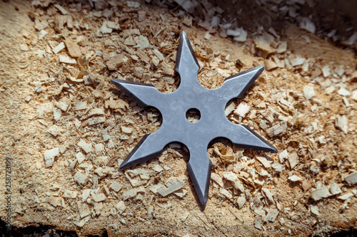 Shuriken (throwing star), traditional japanese ninja cold weapon stuck in wooden background