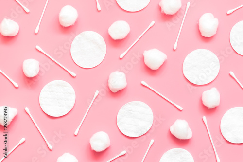 Hygienic background made from cotton balls, pads and swabs on a pink background.