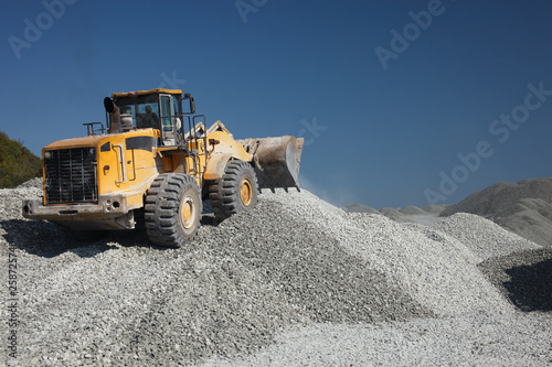 Heavy wheel loader excavator against the background of gravel hills and blue sky. Quarry equipment. Mining industry. photo