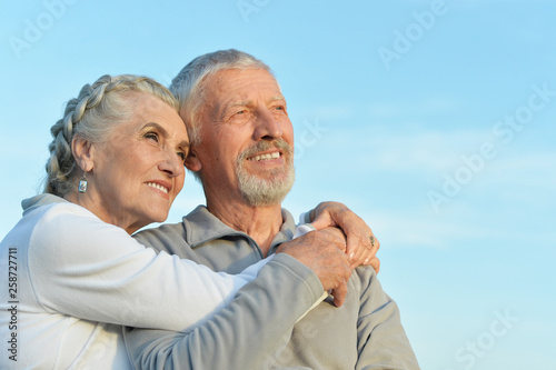 Portrait of senior couple hugging against blue sky