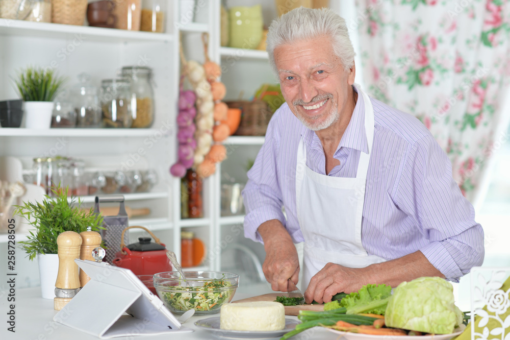 Portrait of senior man preparing dinner in kitchen
