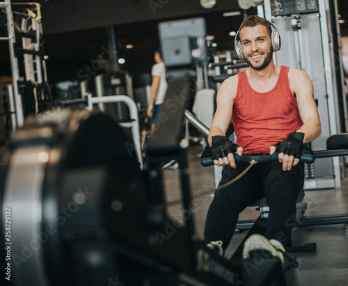 Young man doing workouts on a back with power exercise machine in a gym club