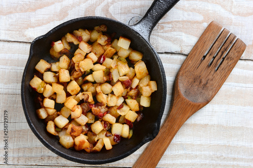 Fried breakfast potatoes in a skillet on a rustic wood table