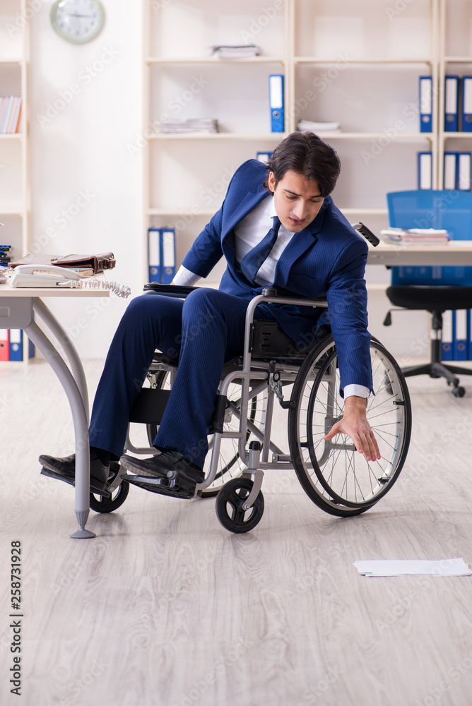 Young male employee in wheelchair working in the office 