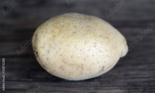 Yellow potatoes on wood background.