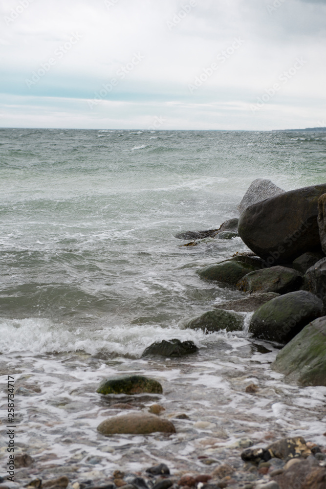 View of the baltic sea and stone beach, stormy sea waves 